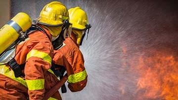 Two firemen spraying water on a fire.